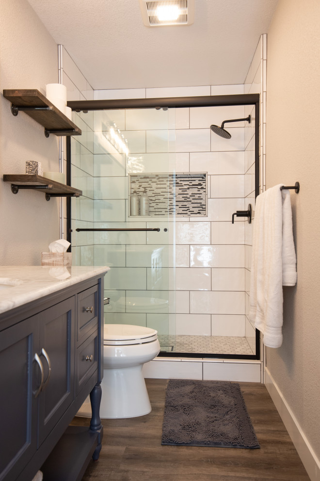 Example of a minimalist bathroom design in Sacramento with blue cabinets, marble countertops and white countertops