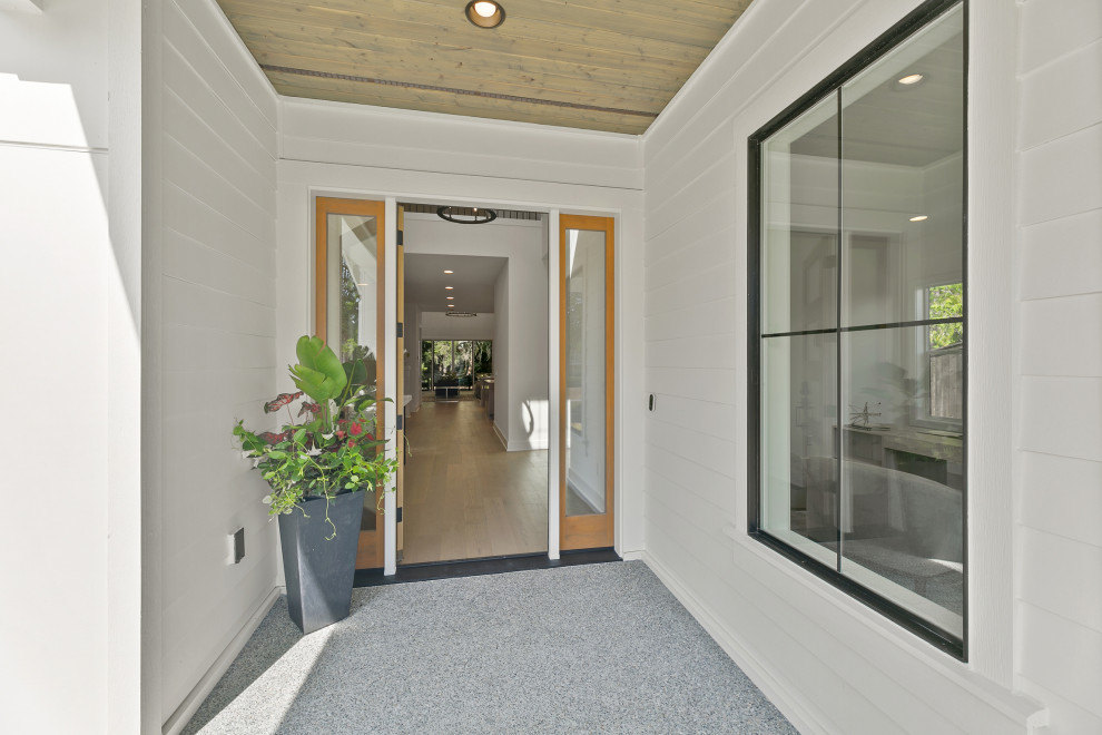 Foto på en stor lantlig ingång och ytterdörr, med vita väggar, betonggolv, en enkeldörr, mellanmörk trädörr och grått golv