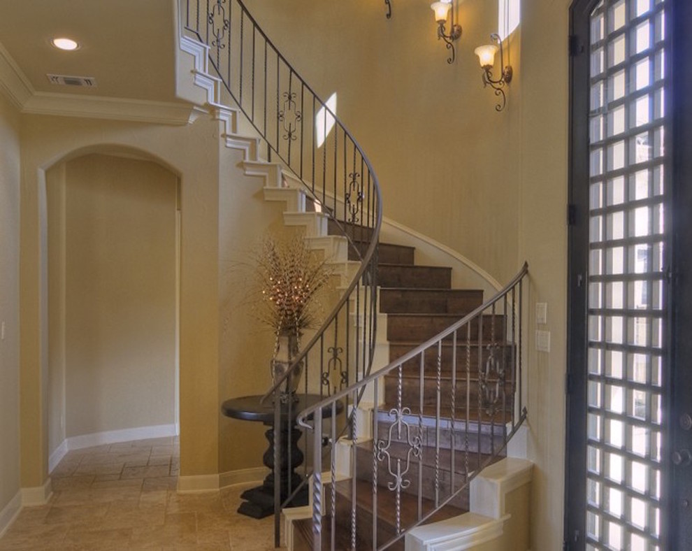 Mid-sized mediterranean wood curved staircase in Austin with wood risers and metal railing.