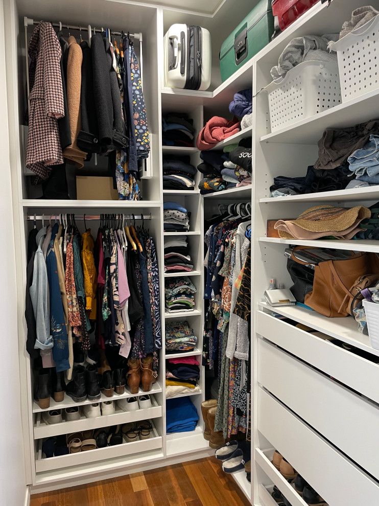 Design ideas for a small contemporary gender-neutral walk-in wardrobe in Wollongong with flat-panel cabinets, white cabinets, light hardwood floors and brown floor.