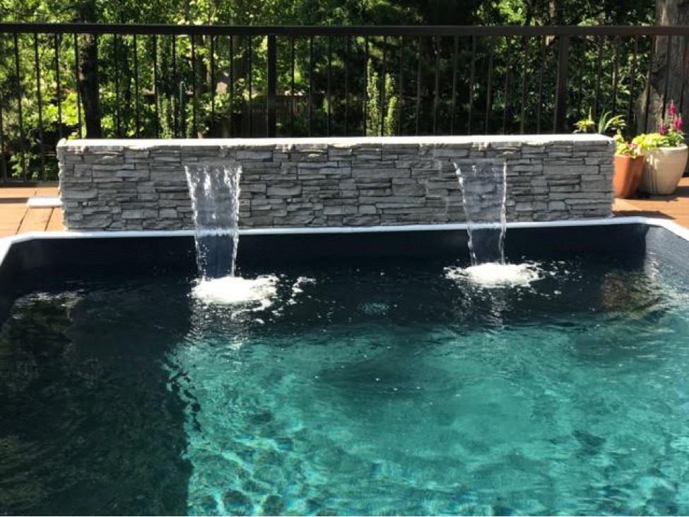 Inspiration for a mid-sized modern backyard rectangular aboveground pool fountain remodel in Detroit with decking