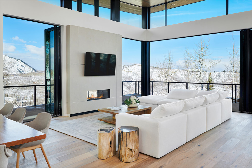 Photo of a large contemporary formal open concept living room in Denver with white walls, light hardwood floors, a two-sided fireplace, a wall-mounted tv, beige floor and a concrete fireplace surround.