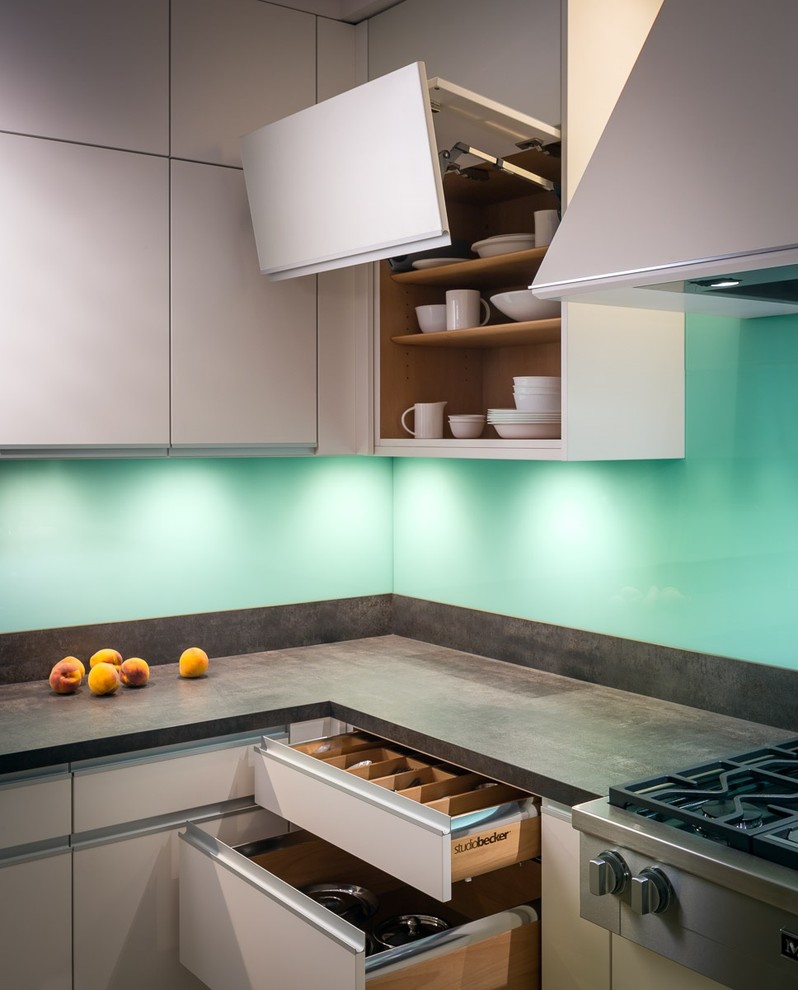 Mid-sized contemporary u-shaped eat-in kitchen in San Francisco with an undermount sink, flat-panel cabinets, beige cabinets, solid surface benchtops, blue splashback, glass sheet splashback, stainless steel appliances, light hardwood floors and a peninsula.