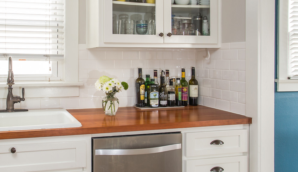 Inspiration for a mid-sized transitional galley medium tone wood floor enclosed kitchen remodel in Santa Barbara with a drop-in sink, shaker cabinets, white cabinets, white backsplash, ceramic backsplash and stainless steel appliances