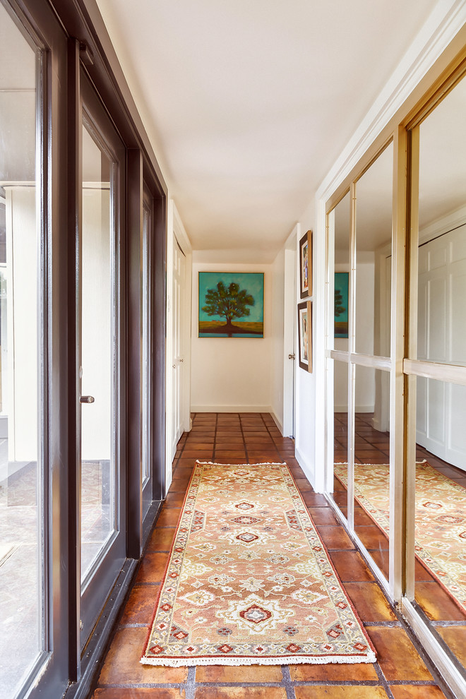 Mid-sized midcentury hallway in Houston with white walls, terra-cotta floors and brown floor.