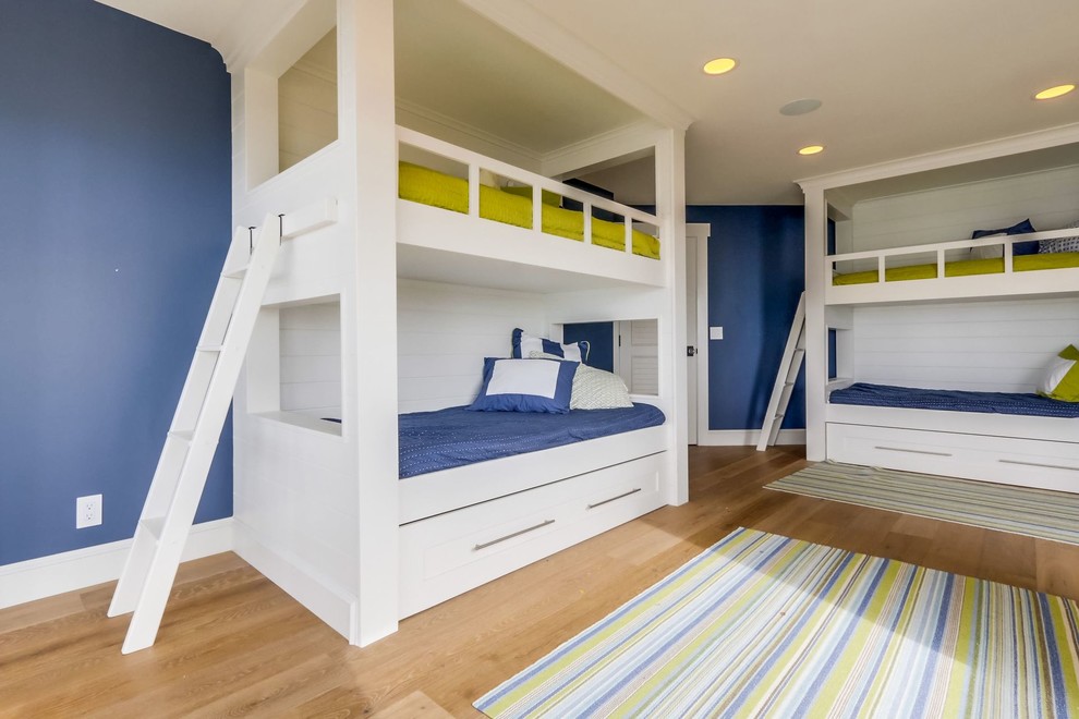 Photo of a large beach style gender-neutral kids' bedroom for kids 4-10 years old in Orange County with blue walls, medium hardwood floors and brown floor.
