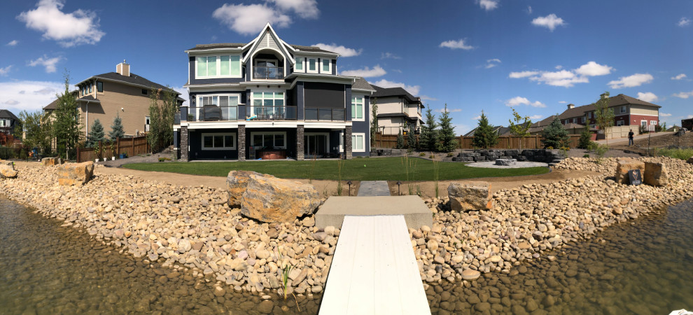 This is an example of a large beach style backyard garden in Calgary with with pond and river rock.