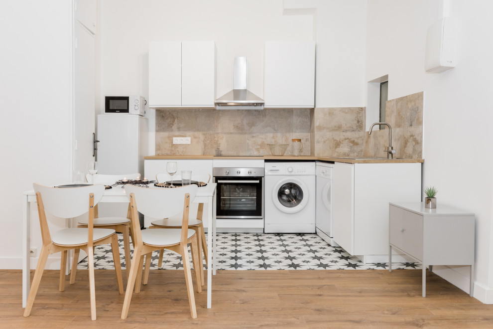 Photo of a contemporary l-shaped kitchen/diner in Marseille with flat-panel cabinets, white cabinets, beige splashback, white appliances, multi-coloured floors and beige worktops.