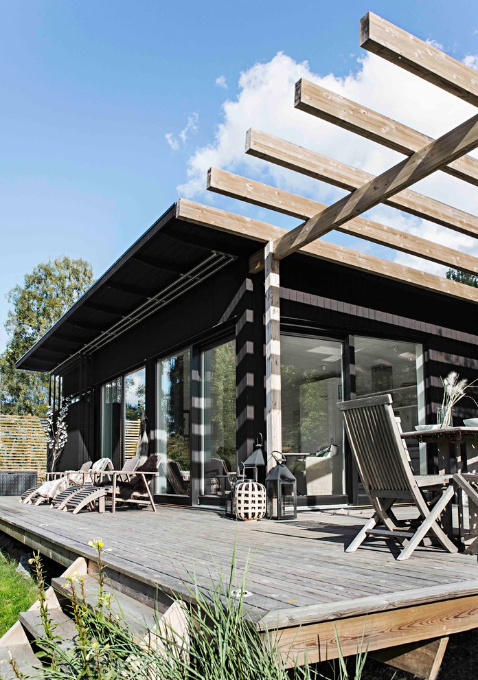 This is an example of a mid-sized scandinavian backyard deck in Stockholm with a pergola.