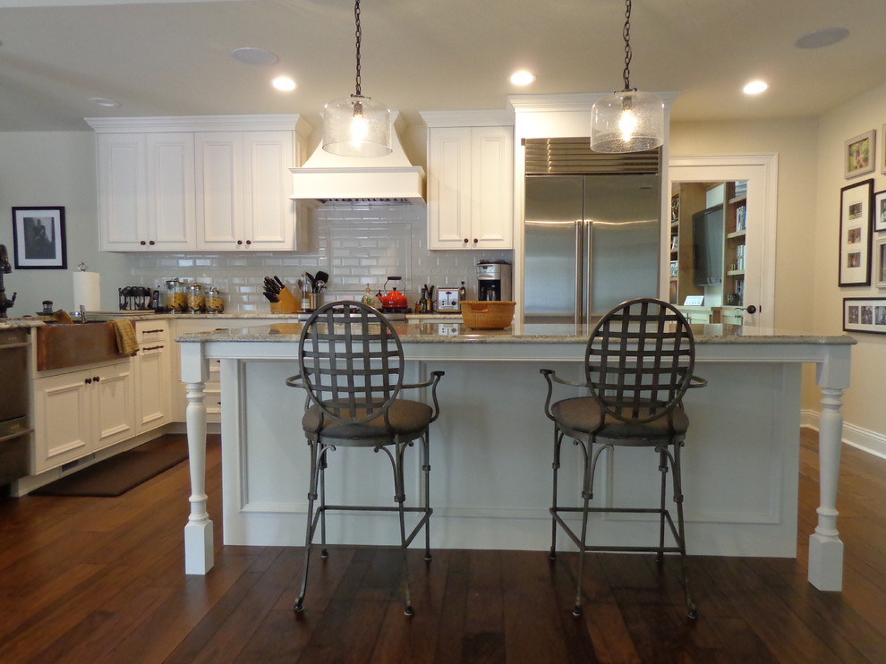 Open concept kitchen - large transitional u-shaped dark wood floor open concept kitchen idea in Raleigh with a farmhouse sink, recessed-panel cabinets, white cabinets, granite countertops, white backsplash, subway tile backsplash, stainless steel appliances and an island