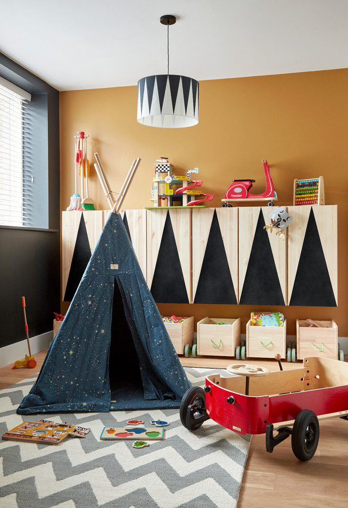 Photo of a small modern gender-neutral kids' playroom for kids 4-10 years old in London with black walls and light hardwood floors.