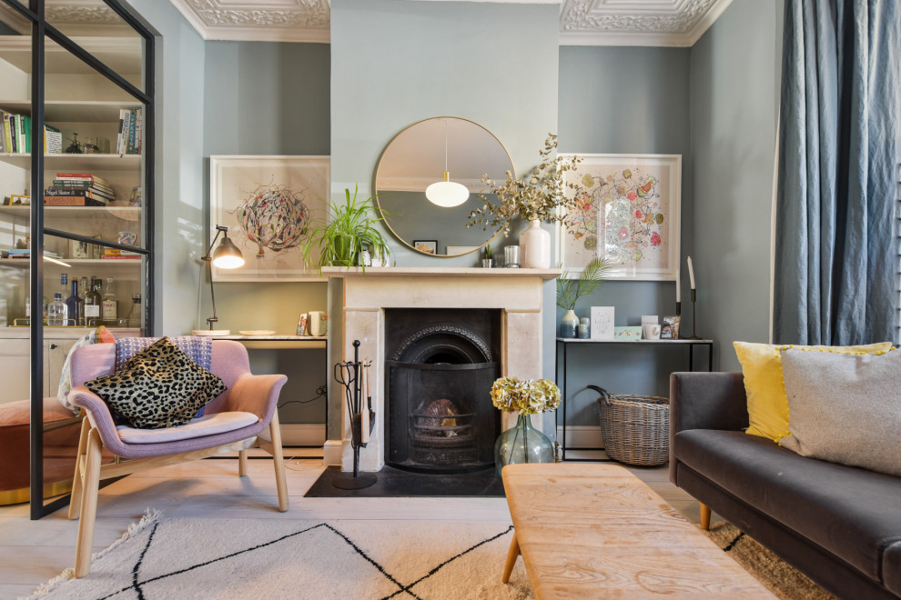 Photo of a mid-sized scandinavian formal enclosed living room in London with light hardwood floors, grey walls, a standard fireplace, a stone fireplace surround and a wall-mounted tv.
