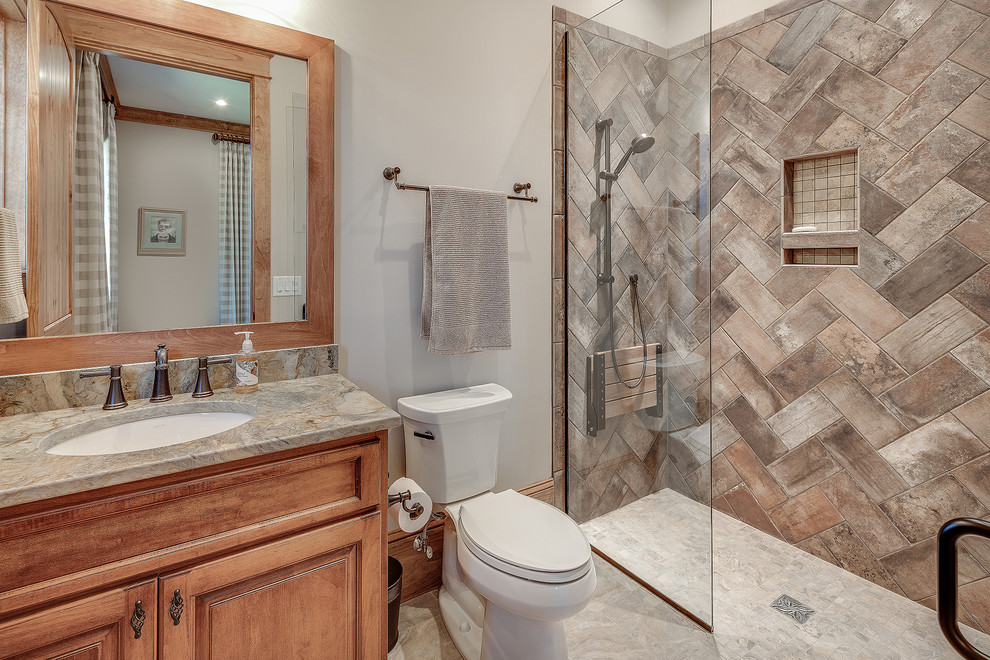 Inspiration for a mid-sized country 3/4 bathroom with shaker cabinets, medium wood cabinets, an alcove shower, a one-piece toilet, beige tile, white walls, an undermount sink, white floor, a hinged shower door and beige benchtops.