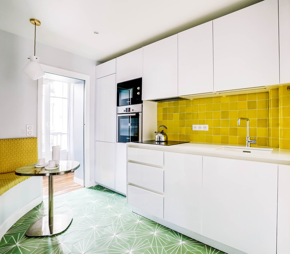 Mid-sized contemporary single-wall open plan kitchen in Paris with an undermount sink, flat-panel cabinets, white cabinets, quartzite benchtops, yellow splashback, terra-cotta splashback, panelled appliances, cement tiles, no island, green floor and white benchtop.