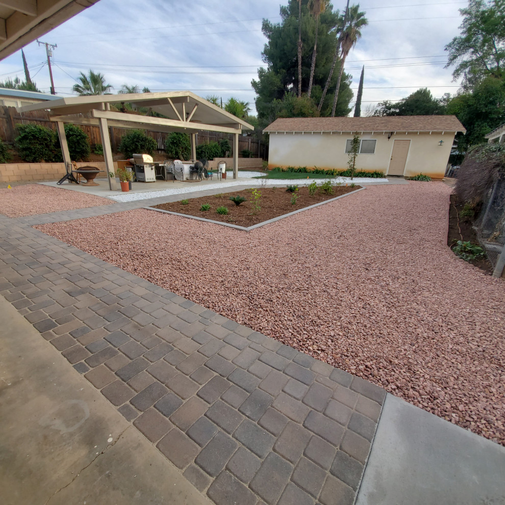 Inspiration for a large transitional backyard full sun xeriscape for spring in Los Angeles with a retaining wall, concrete pavers and a stone fence.
