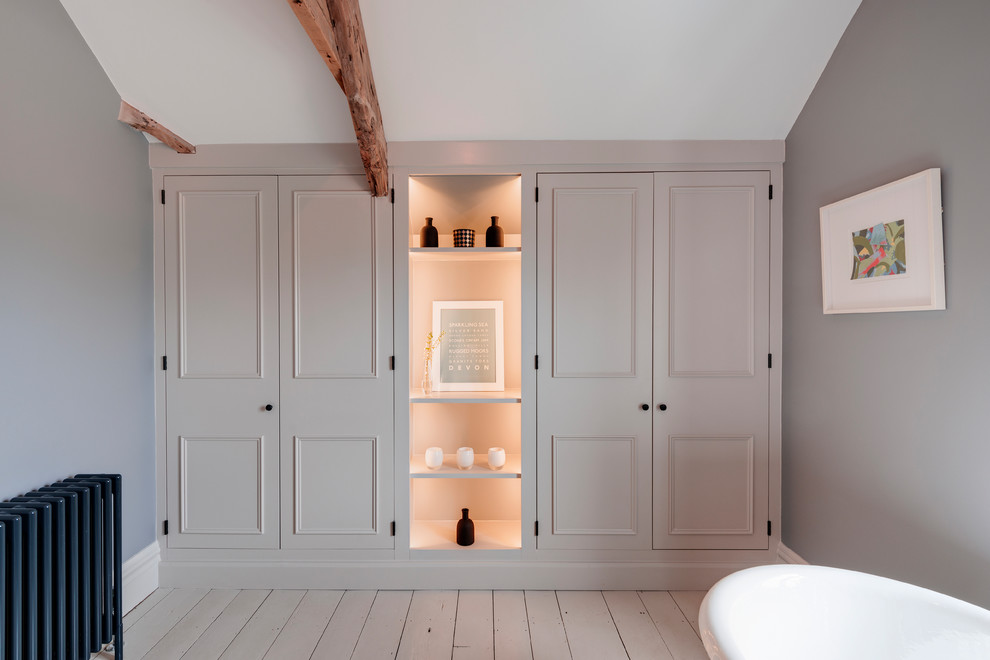 Inspiration for a mid-sized country master bathroom in Devon with beaded inset cabinets, grey cabinets, a freestanding tub, a corner shower, white tile, subway tile, grey walls, painted wood floors, a drop-in sink, grey floor, an open shower and a two-piece toilet.