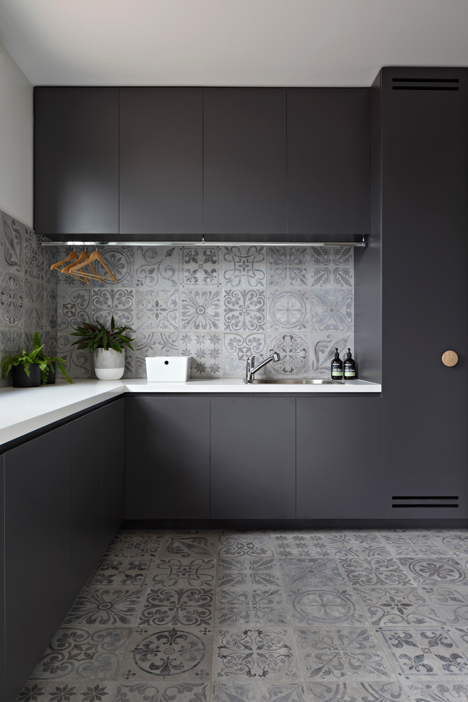 This is an example of a mid-sized contemporary l-shaped utility room in Melbourne with porcelain floors, an undermount sink, flat-panel cabinets, black cabinets, grey floor and white walls.
