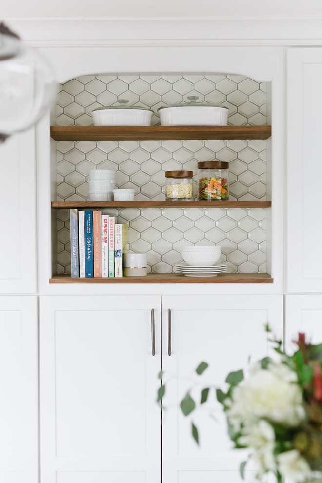 Inspiration for a mid-sized transitional u-shaped medium tone wood floor and brown floor open concept kitchen remodel with an undermount sink, shaker cabinets, white cabinets, quartz countertops, white backsplash, porcelain backsplash, stainless steel appliances, an island and white countertops