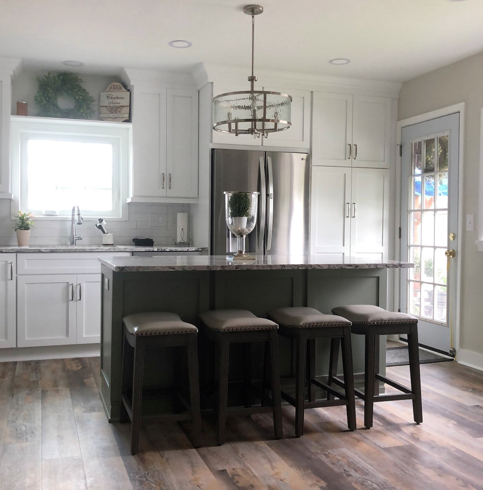 Inspiration for a mid-sized transitional l-shaped vinyl floor and multicolored floor eat-in kitchen remodel with an undermount sink, flat-panel cabinets, green cabinets, quartz countertops, white backsplash, ceramic backsplash, stainless steel appliances, an island and gray countertops