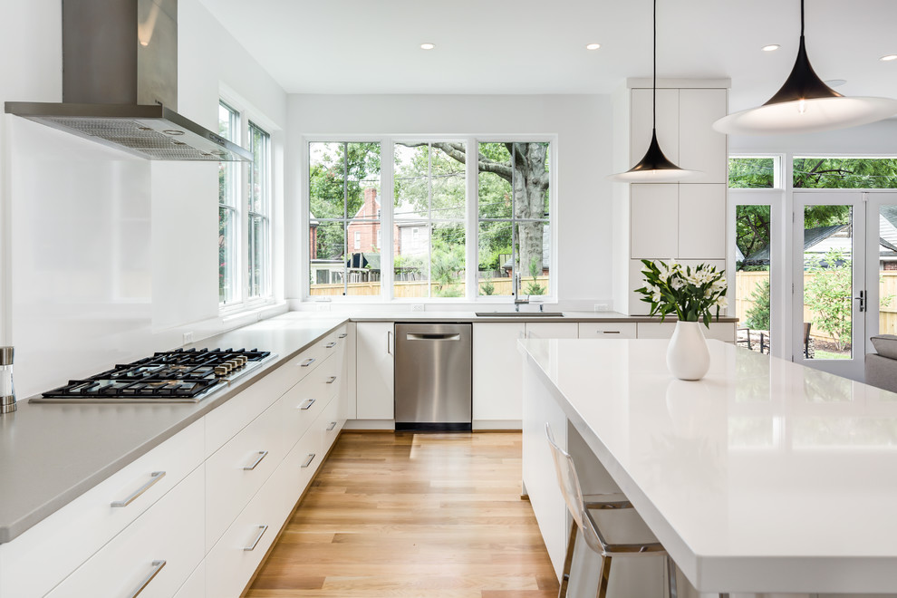 Inspiration for a mid-sized modern l-shaped open plan kitchen in DC Metro with an undermount sink, flat-panel cabinets, white cabinets, quartzite benchtops, stainless steel appliances, light hardwood floors, with island and beige floor.