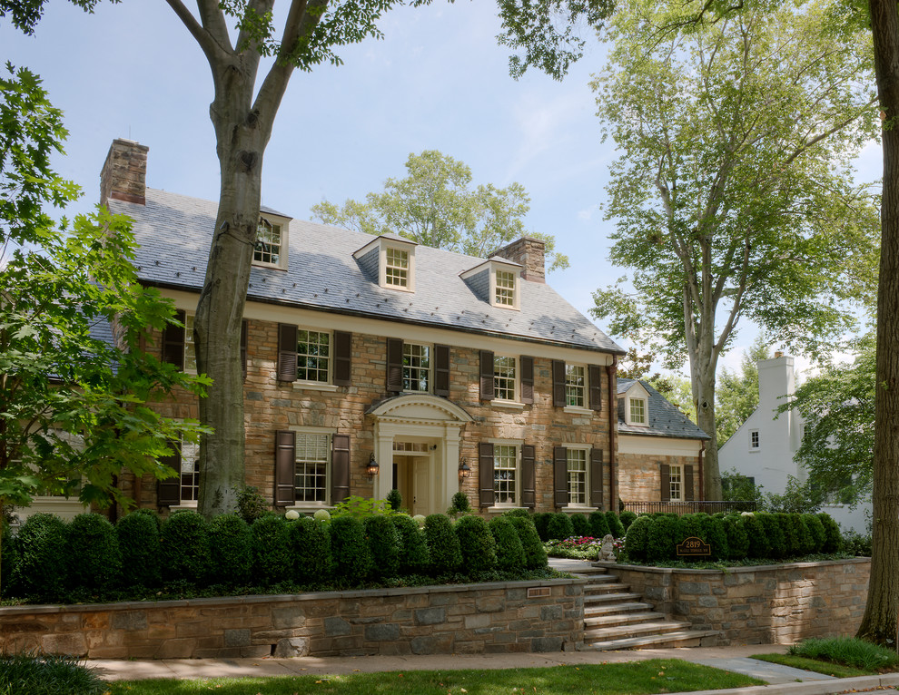 Photo of a large traditional three-storey exterior in DC Metro with stone veneer and a gable roof.