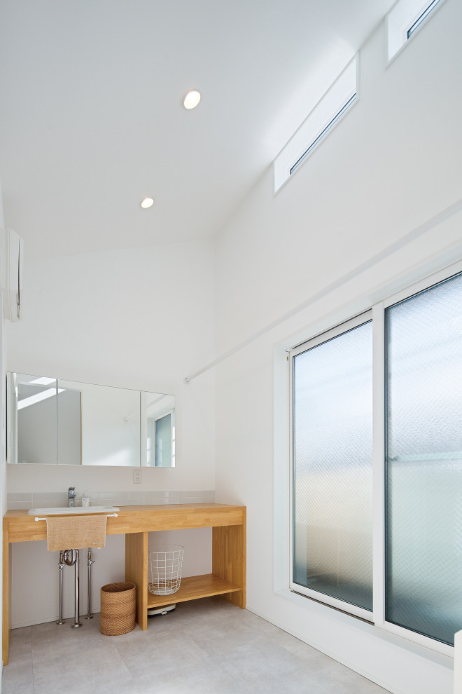 Mid-sized modern single-wall dedicated laundry room in Tokyo with an undermount sink, open cabinets, brown cabinets, wood benchtops, white walls, porcelain floors, grey floor and brown benchtop.