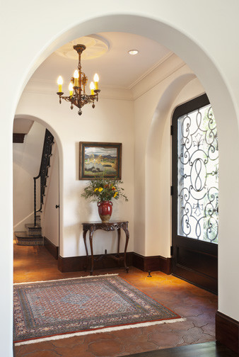 Mediterranean entryway in San Diego with white walls, terra-cotta floors and a single front door.