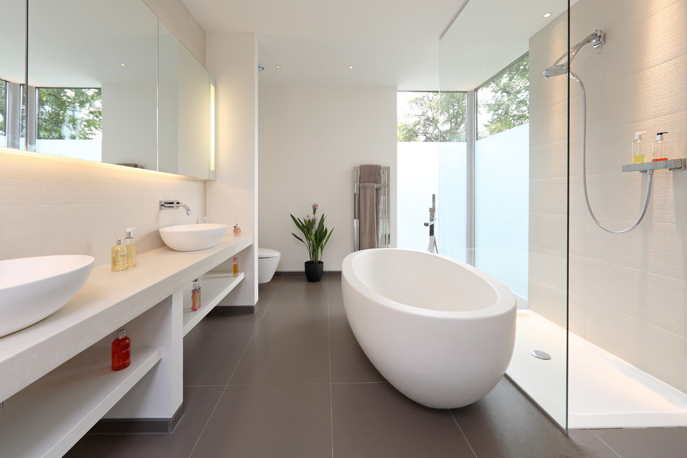 Photo of a contemporary bathroom in Other with a vessel sink, open cabinets, white cabinets, a freestanding tub, an open shower, white tile, white walls and an open shower.