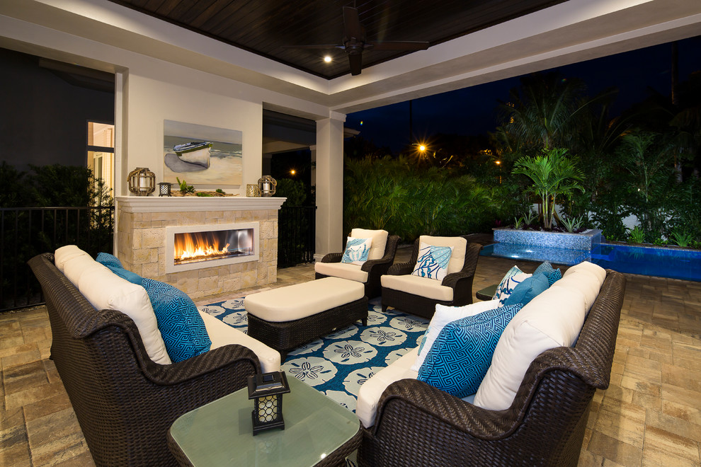 Large beach style backyard patio in Miami with a fire feature and a roof extension.