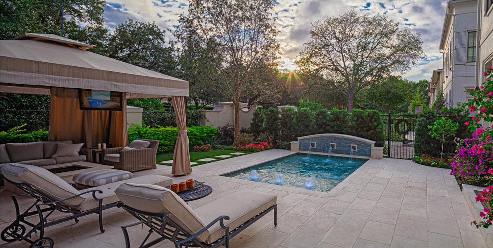 Design ideas for a small traditional front yard rectangular pool in Houston with a water feature and natural stone pavers.