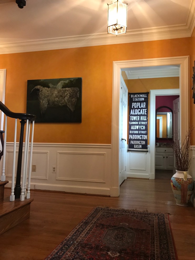 This is an example of a mid-sized transitional foyer in DC Metro with orange walls, light hardwood floors, a single front door and a black front door.
