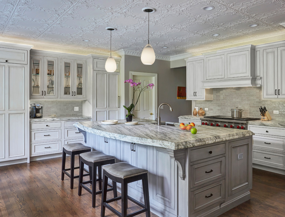 Inspiration for a traditional l-shaped kitchen in Chicago with an undermount sink, grey cabinets, quartzite benchtops, grey splashback, glass tile splashback, panelled appliances, dark hardwood floors, recessed-panel cabinets, with island and brown floor.