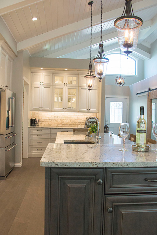 Example of a large transitional l-shaped eat-in kitchen design with a double-bowl sink, shaker cabinets, white cabinets, beige backsplash, stainless steel appliances and an island