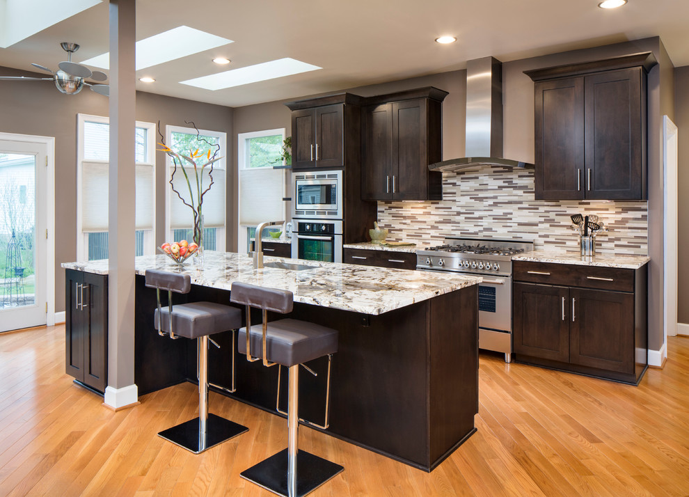 Transitional galley medium tone wood floor kitchen photo in DC Metro with shaker cabinets, dark wood cabinets, multicolored backsplash, matchstick tile backsplash, stainless steel appliances, an island and an undermount sink