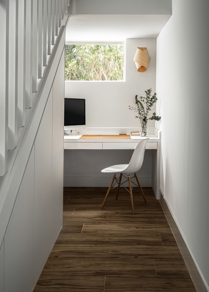 Cette image montre un bureau nordique avec un mur blanc, un bureau intégré et un sol marron.