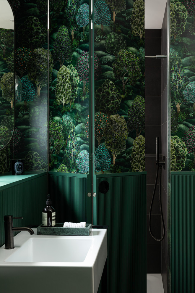 Inspiration for a traditional powder room in London with open cabinets, dark wood cabinets, green tile, green walls, porcelain floors, a console sink, brown floor, a freestanding vanity and wallpaper.