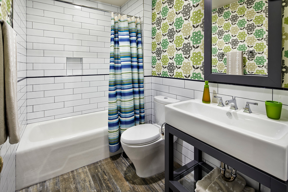 Mid-sized transitional kids bathroom in Denver with an alcove tub, a shower/bathtub combo, a two-piece toilet, white tile, subway tile, a console sink, dark hardwood floors, multi-coloured walls and brown floor.