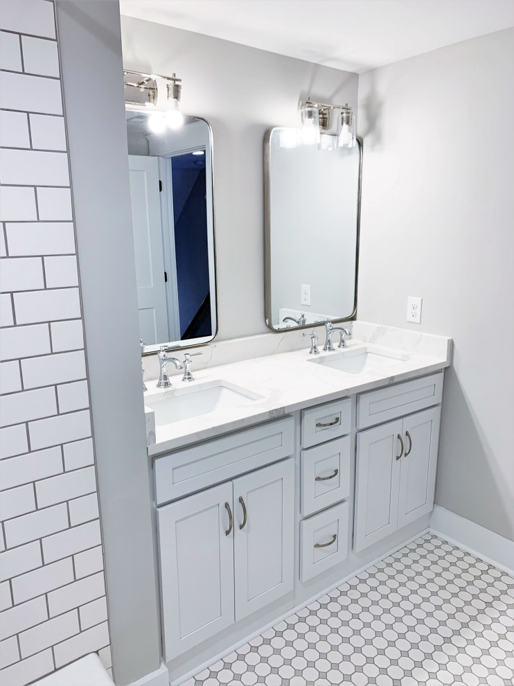 This is an example of a mid-sized traditional kids bathroom in Richmond with recessed-panel cabinets, white cabinets, an alcove tub, a shower/bathtub combo, a two-piece toilet, grey walls, ceramic floors, an undermount sink, solid surface benchtops, multi-coloured floor, a shower curtain, white benchtops, a double vanity and a built-in vanity.
