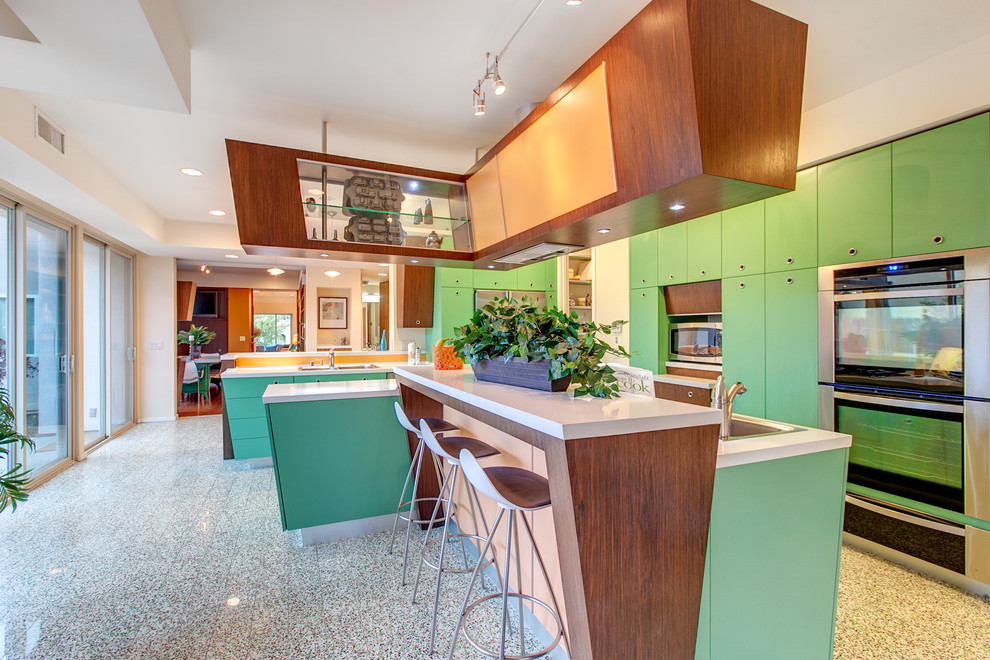 Midcentury l-shaped open plan kitchen in San Diego with flat-panel cabinets, quartz benchtops, stainless steel appliances, with island and green cabinets.