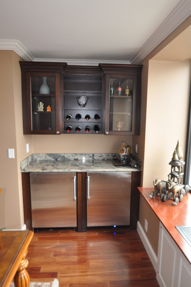 Photo of a mid-sized traditional single-wall wet bar in Boston with glass-front cabinets, dark wood cabinets, marble benchtops and medium hardwood floors.