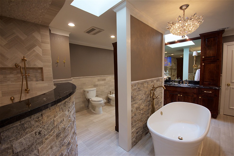 Inspiration for a large contemporary master bathroom in Austin with beaded inset cabinets, dark wood cabinets, a freestanding tub, an open shower, a bidet, beige tile, beige walls, a drop-in sink, granite benchtops, vinyl floors and beige floor.