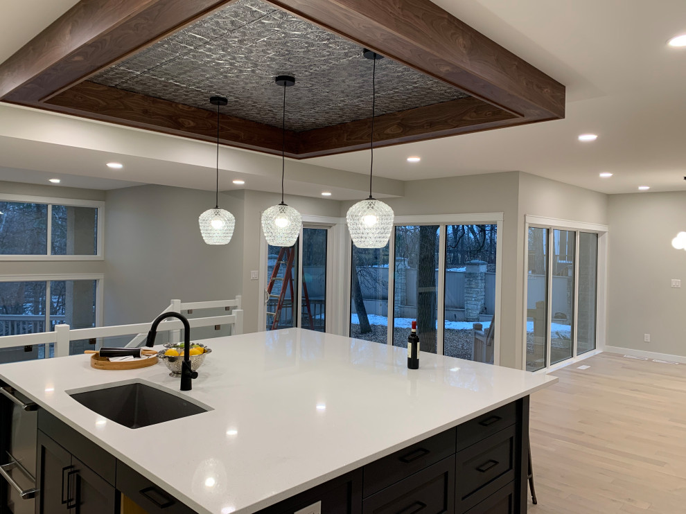 Inspiration for a large transitional light wood floor and coffered ceiling kitchen remodel with an undermount sink, shaker cabinets, white cabinets, quartzite countertops, stainless steel appliances, an island and white countertops
