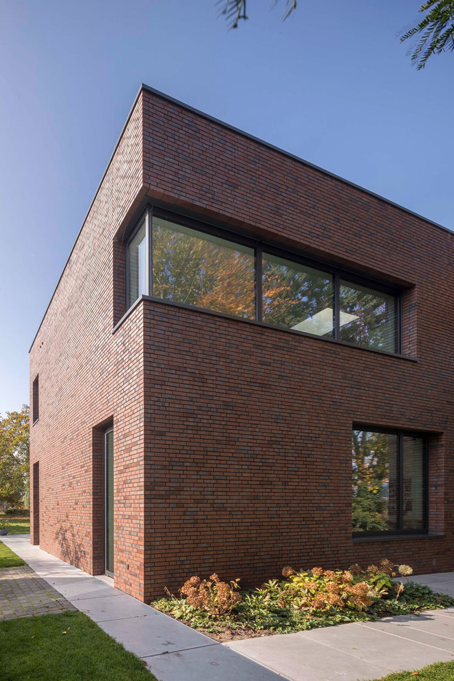 Modern two-storey brick red house exterior in Other with a flat roof.