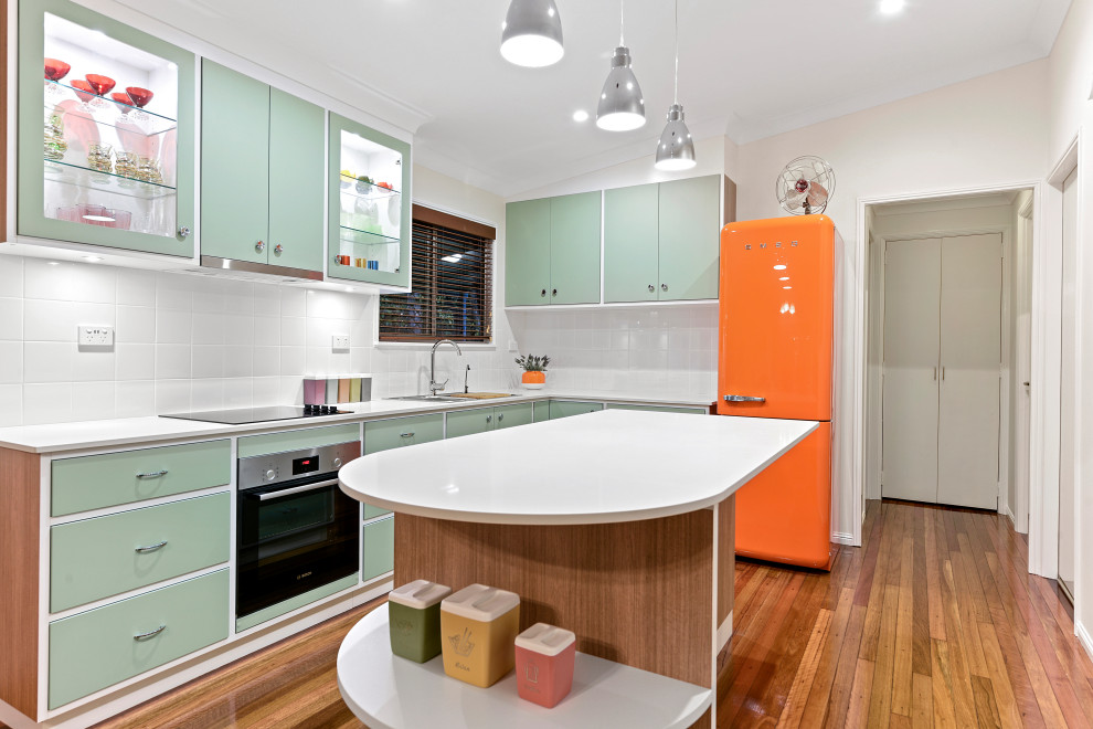 Design ideas for a contemporary l-shaped kitchen in Brisbane with an undermount sink, flat-panel cabinets, green cabinets, white splashback, coloured appliances, medium hardwood floors, with island, brown floor, white benchtop and vaulted.