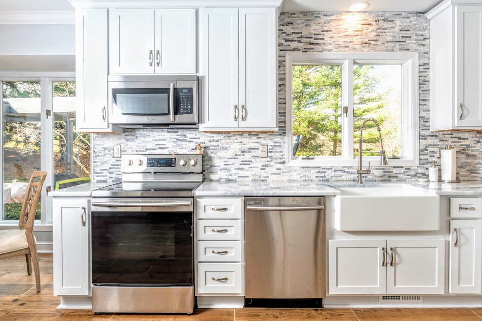 Large transitional l-shaped ceramic tile and brown floor eat-in kitchen photo in Baltimore with a farmhouse sink, shaker cabinets, white cabinets, granite countertops, gray backsplash, stone tile backsplash, stainless steel appliances, no island and white countertops