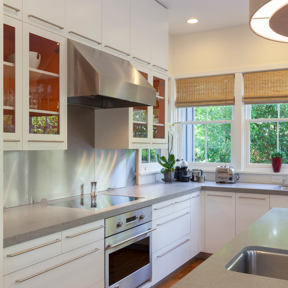 This is an example of a mid-sized contemporary l-shaped eat-in kitchen in San Francisco with a double-bowl sink, flat-panel cabinets, white cabinets, quartz benchtops, metallic splashback, metal splashback, stainless steel appliances, medium hardwood floors and with island.