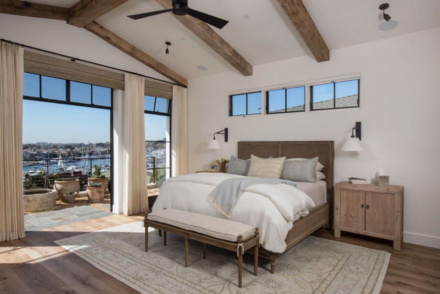 Large mediterranean master bedroom in Orange County with white walls and medium hardwood floors.