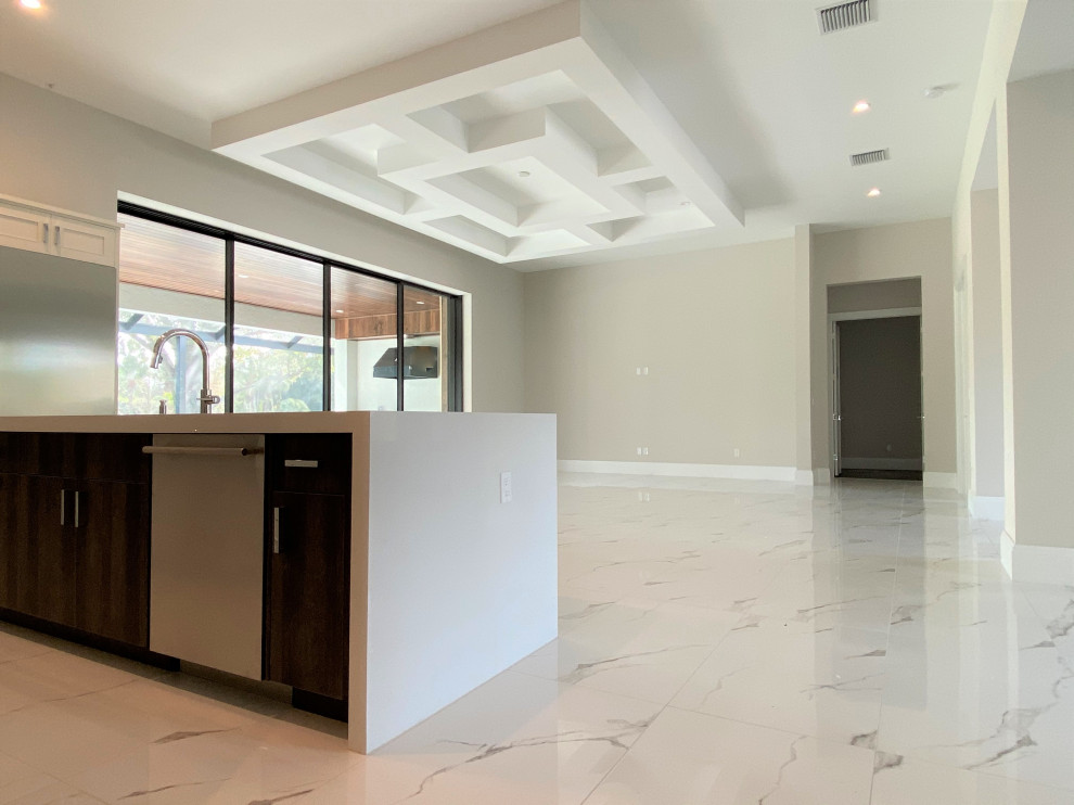 Open concept kitchen - mid-sized transitional l-shaped porcelain tile and white floor open concept kitchen idea in Miami with an undermount sink, recessed-panel cabinets, beige cabinets, quartz countertops, white backsplash, porcelain backsplash, stainless steel appliances, an island and white countertops