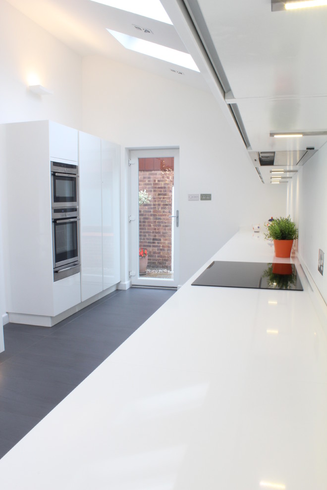 Inspiration for a mid-sized modern eat-in kitchen in Hertfordshire with an undermount sink, flat-panel cabinets, white cabinets, quartz benchtops, stainless steel appliances, porcelain floors and with island.