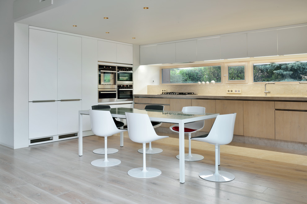 Inspiration for a mid-sized contemporary u-shaped kitchen in Moscow with flat-panel cabinets, light wood cabinets, stainless steel appliances, light hardwood floors, no island, beige floor, beige splashback and beige benchtop.